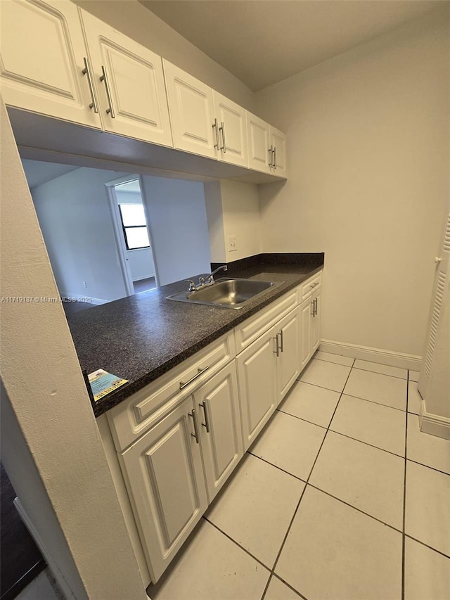 kitchen with sink, white cabinets, and light tile patterned flooring