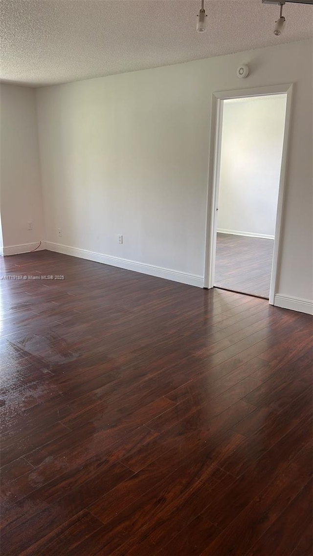 unfurnished room featuring dark wood-type flooring and a textured ceiling