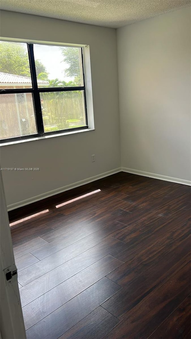 spare room featuring a textured ceiling and dark wood-type flooring