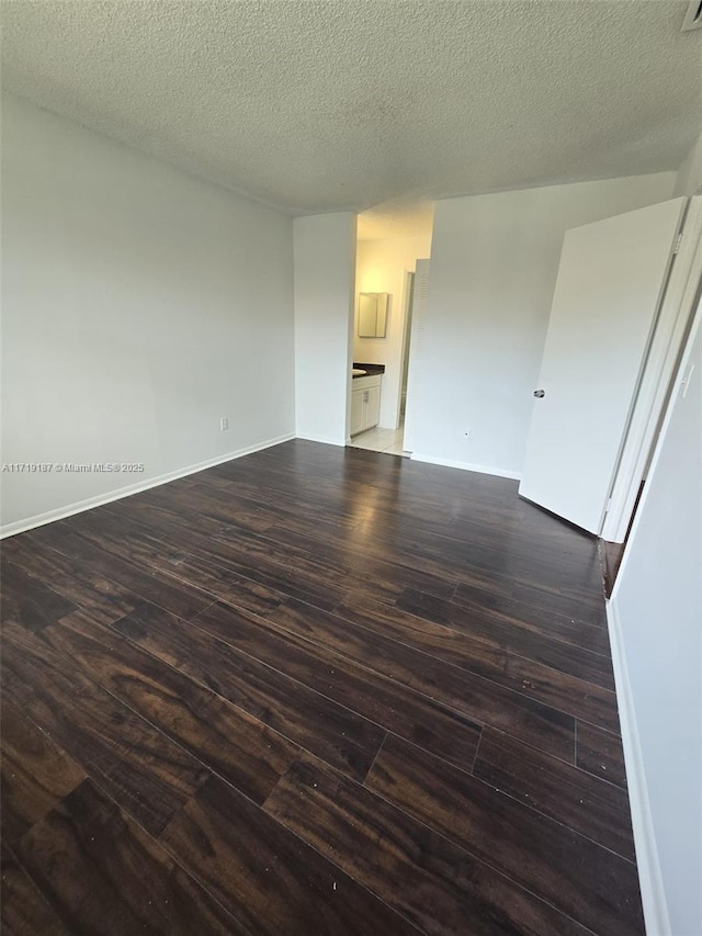 empty room with dark hardwood / wood-style flooring and a textured ceiling