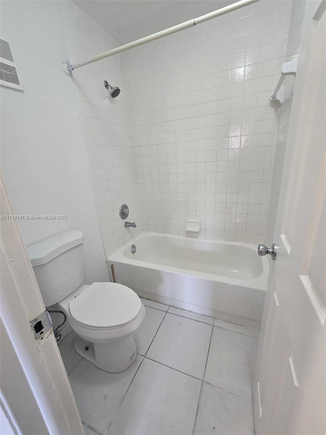 bathroom with tile patterned flooring, tiled shower / bath combo, and toilet