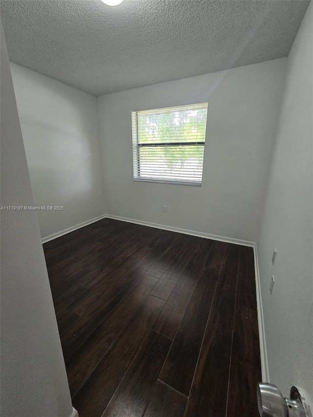 unfurnished room with dark hardwood / wood-style flooring and a textured ceiling