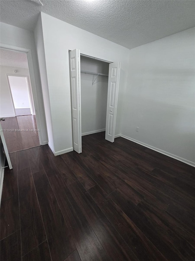 unfurnished bedroom with a closet, dark hardwood / wood-style flooring, and a textured ceiling