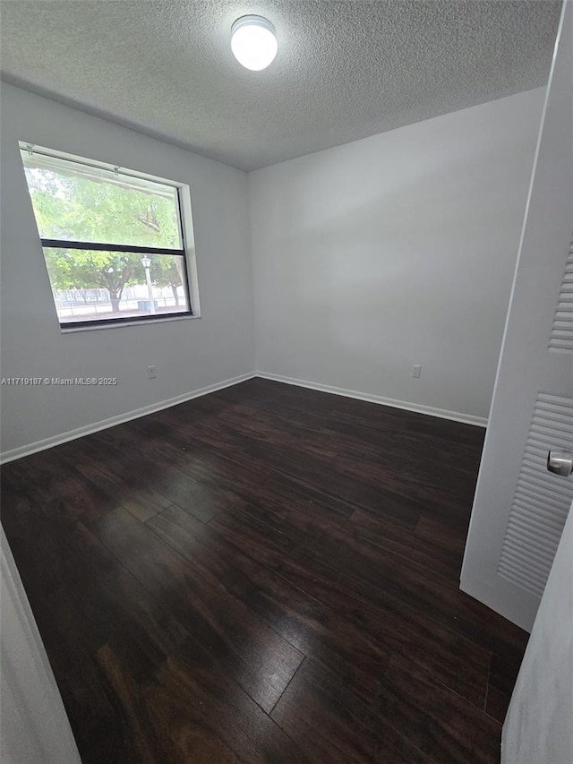 empty room featuring a textured ceiling and dark wood-type flooring