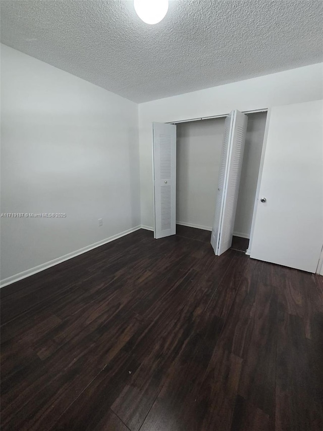 unfurnished bedroom with two closets, dark hardwood / wood-style flooring, and a textured ceiling