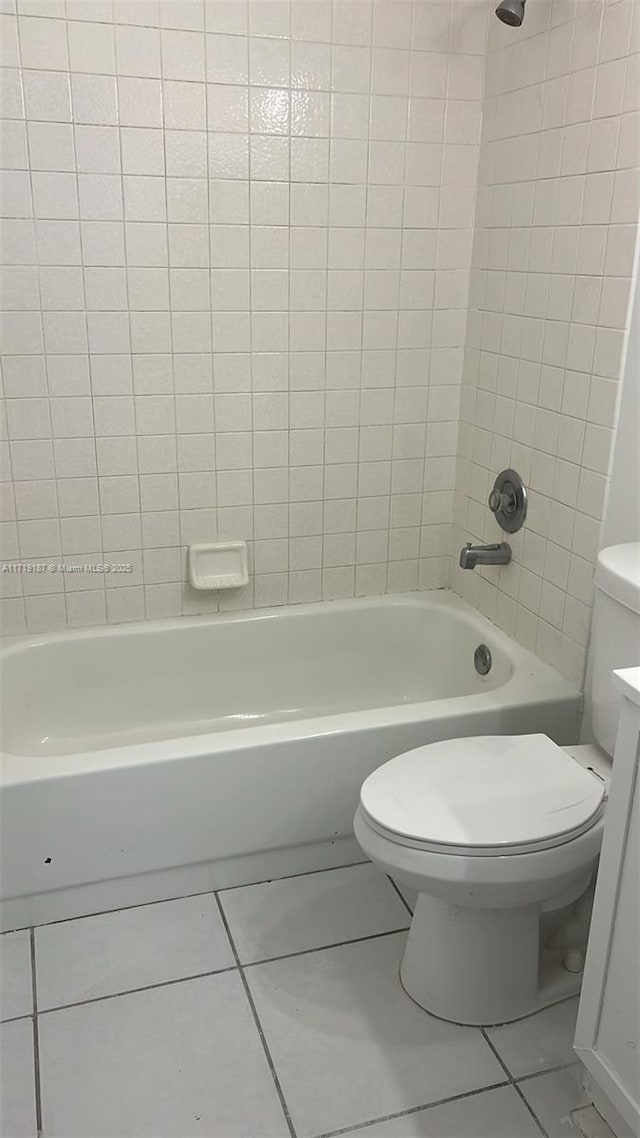 bathroom with tile patterned flooring, toilet, and washtub / shower combination