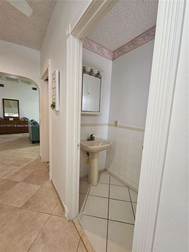 bathroom featuring tile patterned floors, sink, a textured ceiling, and tile walls