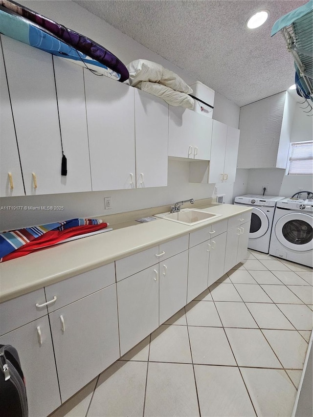 laundry room with sink, cabinets, washing machine and dryer, a textured ceiling, and light tile patterned flooring