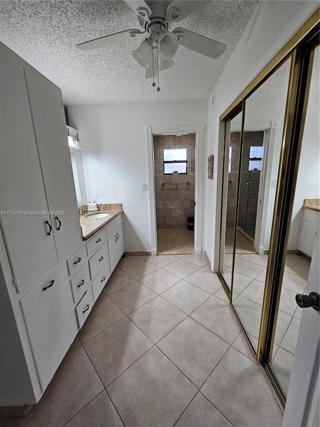 bathroom featuring tile patterned floors, vanity, an enclosed shower, and a textured ceiling