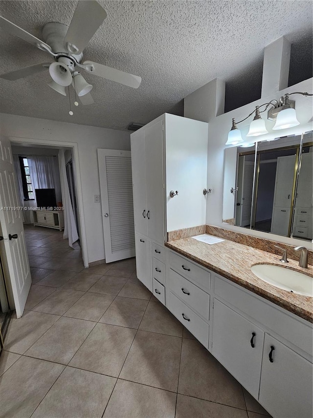 bathroom with a textured ceiling, vanity, tile patterned floors, and ceiling fan