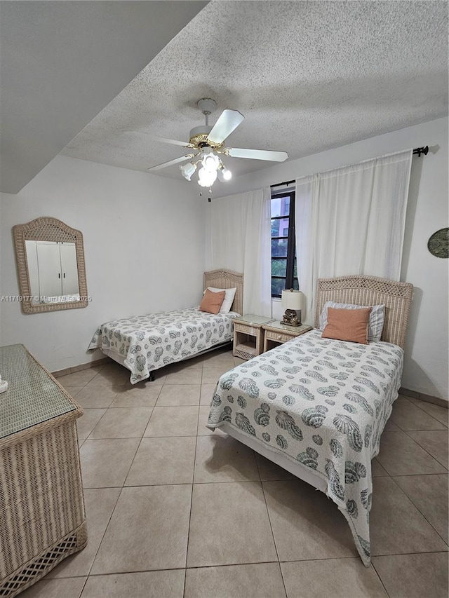 bedroom with a textured ceiling, ceiling fan, and light tile patterned flooring