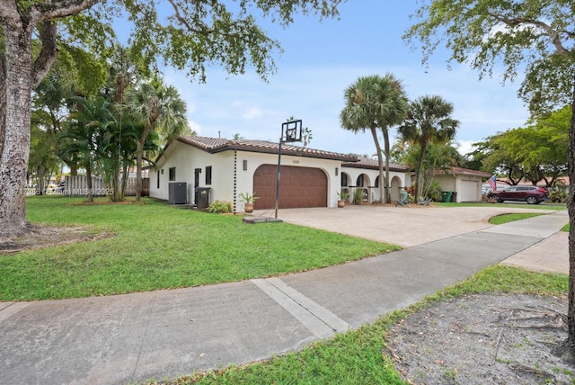 mediterranean / spanish-style home featuring central air condition unit, a front yard, and a garage