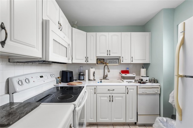 kitchen featuring white appliances, white cabinets, sink, decorative backsplash, and light tile patterned floors