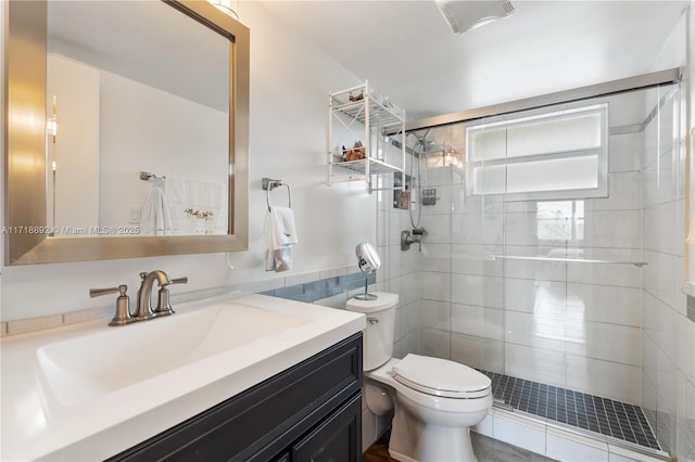 bathroom with vanity, toilet, a shower with door, and tile walls