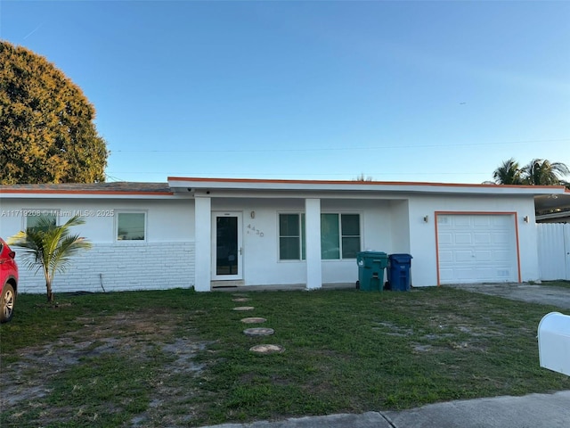 single story home with a front yard, brick siding, an attached garage, and stucco siding