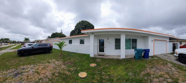 view of front of property with a garage, a front lawn, and stucco siding