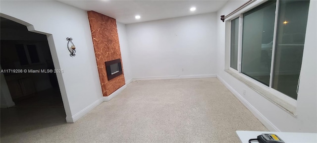 unfurnished living room featuring recessed lighting, a fireplace, and baseboards