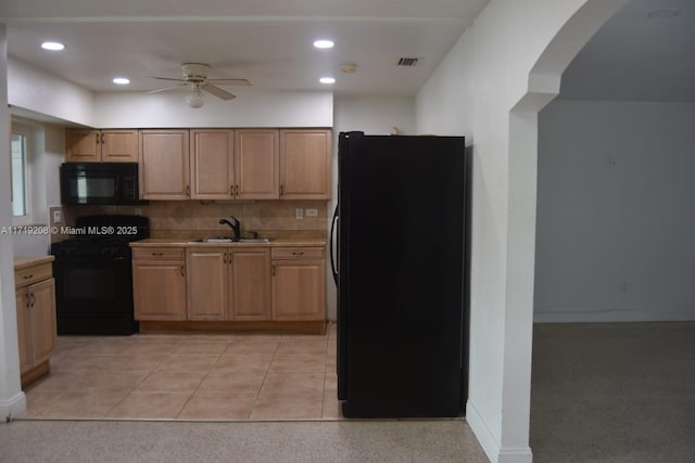 kitchen featuring ceiling fan, a sink, light countertops, decorative backsplash, and black appliances