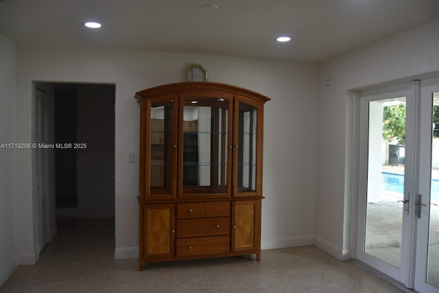 interior space with baseboards, light speckled floor, and recessed lighting