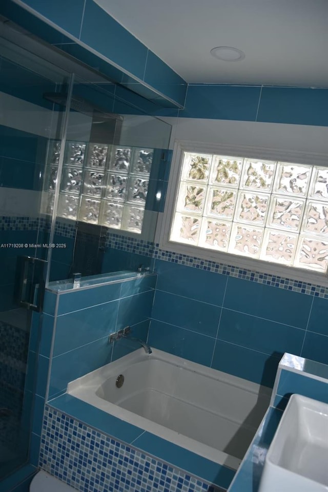 bathroom with a tub to relax in, a stall shower, and a sink