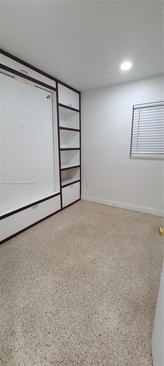 empty room with baseboards and speckled floor