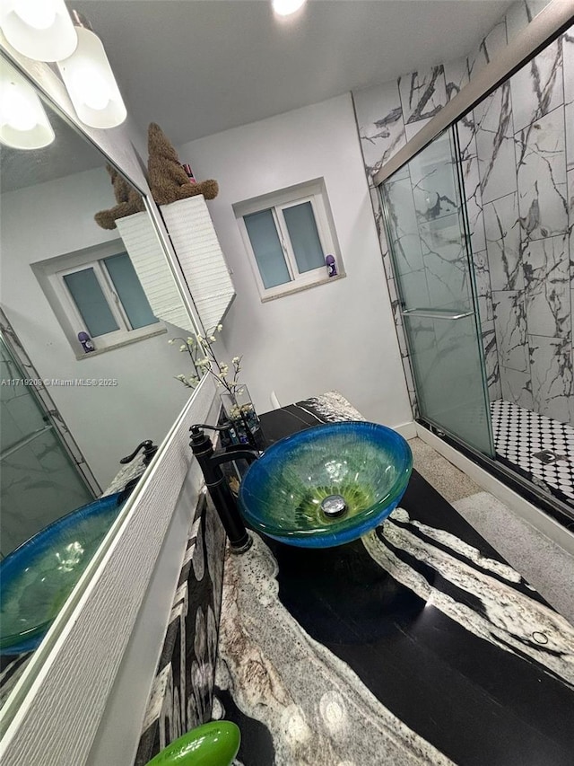 full bath with a sink and a marble finish shower