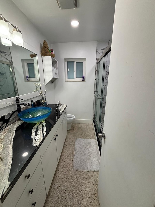 full bathroom with toilet, vanity, a marble finish shower, and speckled floor