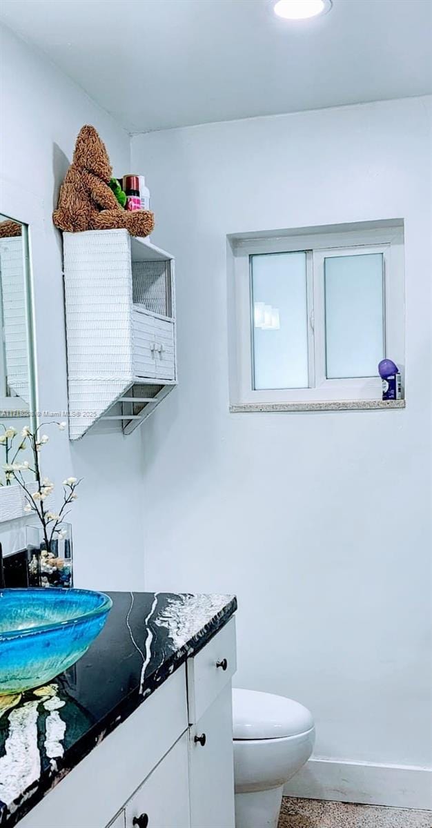 bathroom with toilet, baseboards, speckled floor, and vanity