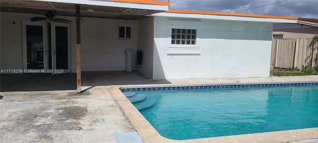 pool with fence and a ceiling fan