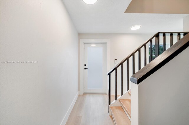 kitchen with stainless steel refrigerator, light hardwood / wood-style flooring, kitchen peninsula, a kitchen bar, and white cabinets