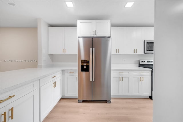 kitchen featuring light wood-type flooring, light stone countertops, white cabinets, and appliances with stainless steel finishes