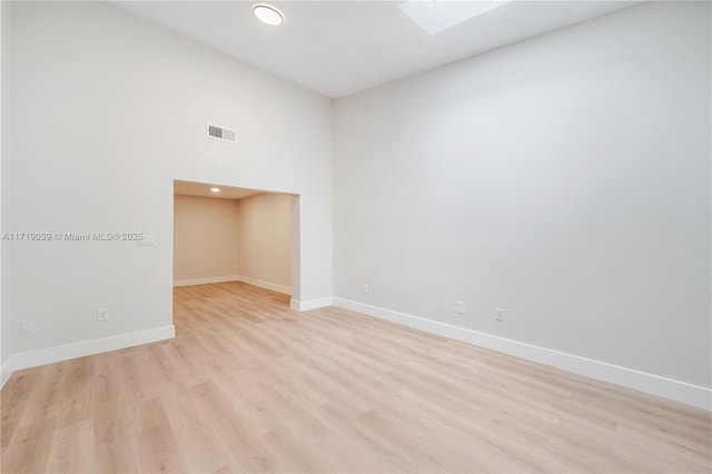 spare room with a skylight and light wood-type flooring