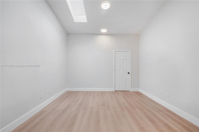 empty room with a skylight and light hardwood / wood-style floors