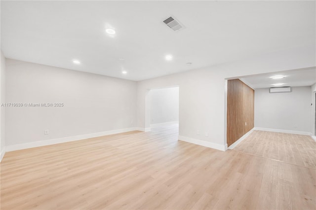 empty room featuring a wall mounted air conditioner and light hardwood / wood-style flooring