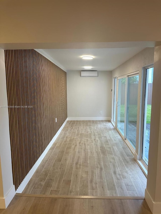 empty room with an AC wall unit and light hardwood / wood-style flooring