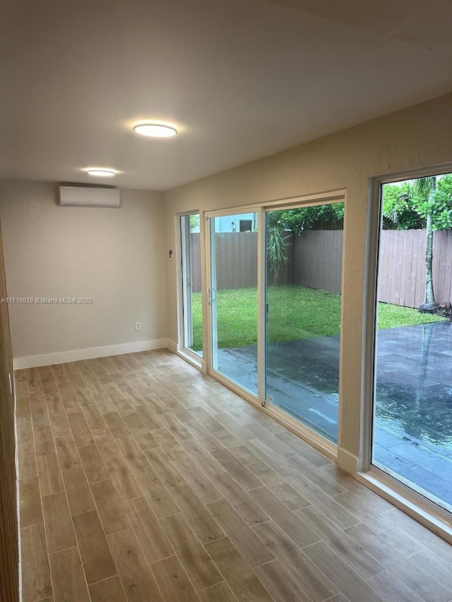 unfurnished room featuring a wall unit AC and light hardwood / wood-style floors