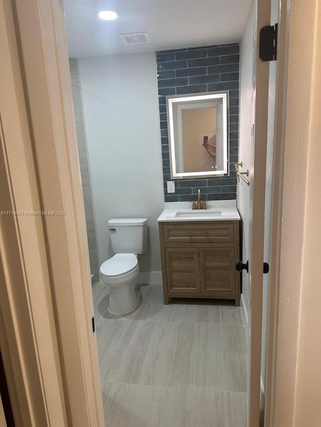 bathroom featuring vanity, backsplash, and toilet