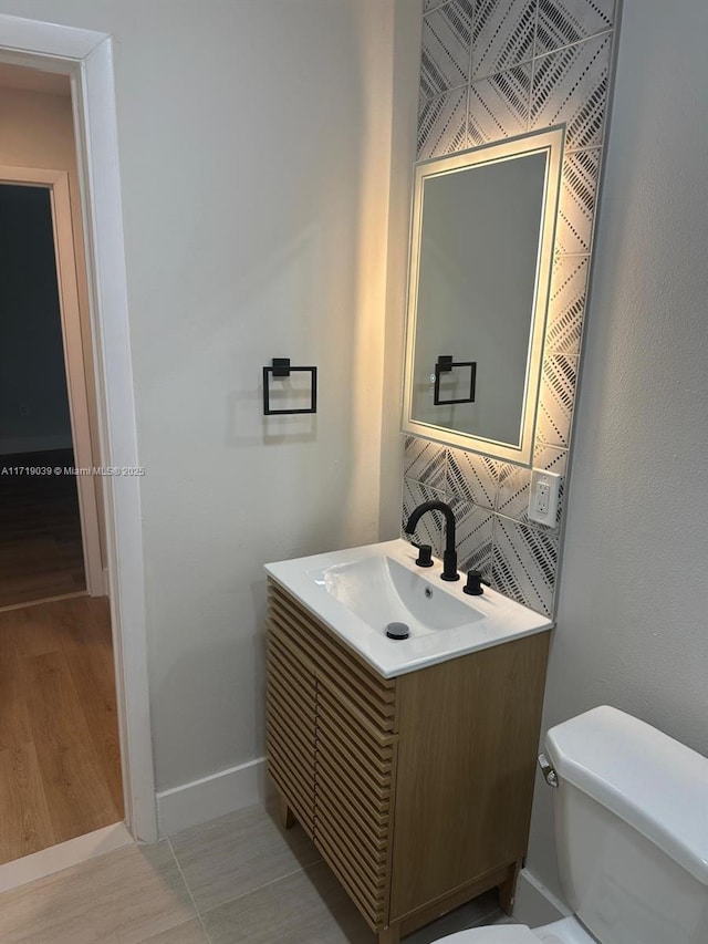 bathroom featuring vanity, decorative backsplash, and toilet