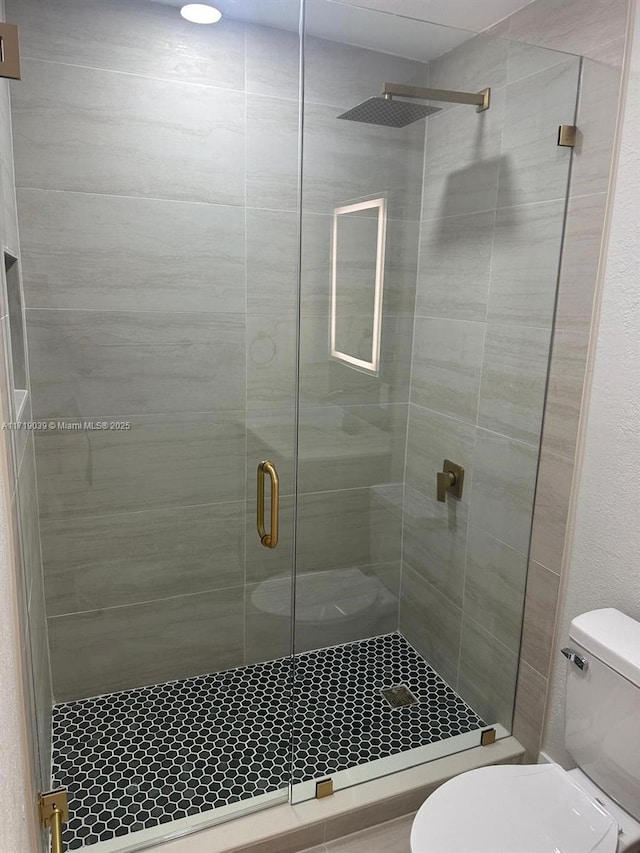 bathroom featuring a shower with shower door and toilet