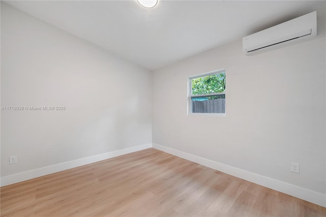 spare room with a wall unit AC and light hardwood / wood-style floors