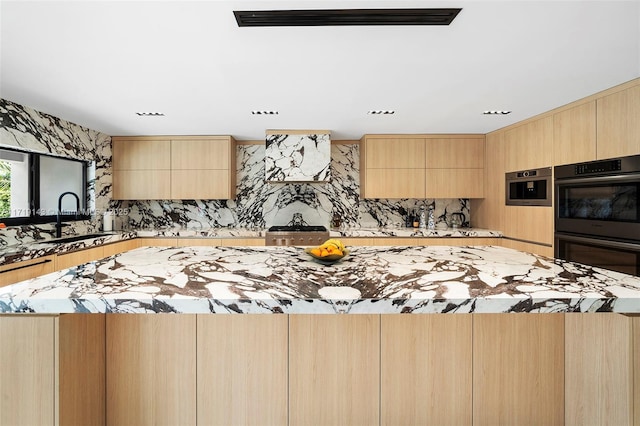 kitchen featuring light brown cabinetry, a kitchen island, double oven, and sink