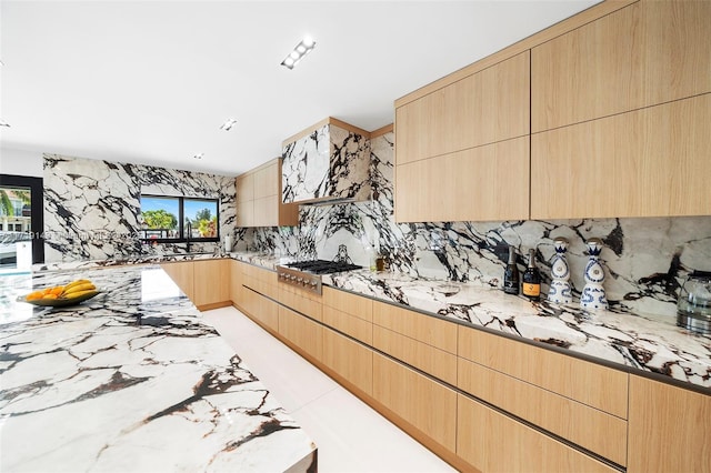 kitchen featuring light stone countertops, decorative backsplash, sink, light brown cabinets, and stainless steel gas stovetop