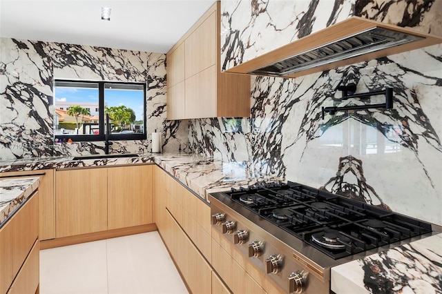 kitchen with stainless steel gas stovetop, sink, premium range hood, and light brown cabinetry