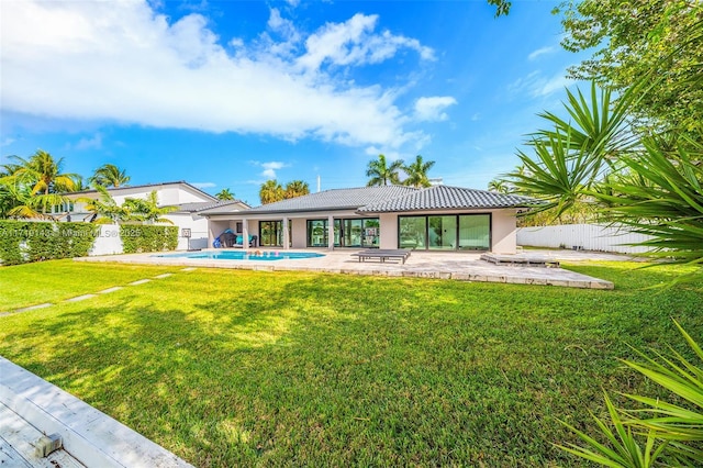 rear view of property featuring a yard, a patio, and a fenced in pool