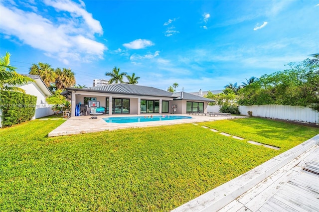 back of property with a yard, a fenced in pool, and a patio area