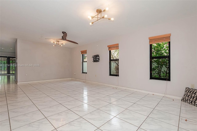 unfurnished room with ceiling fan with notable chandelier and plenty of natural light