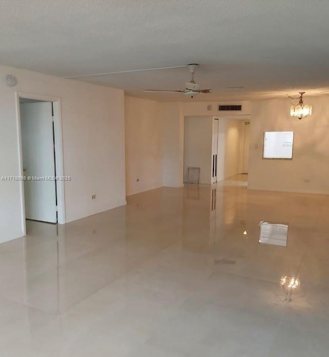 spare room with ceiling fan with notable chandelier