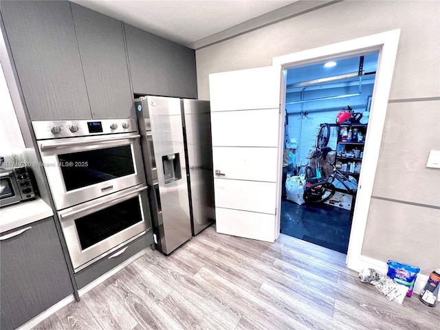 kitchen with gray cabinets, stainless steel fridge with ice dispenser, double wall oven, and light hardwood / wood-style floors