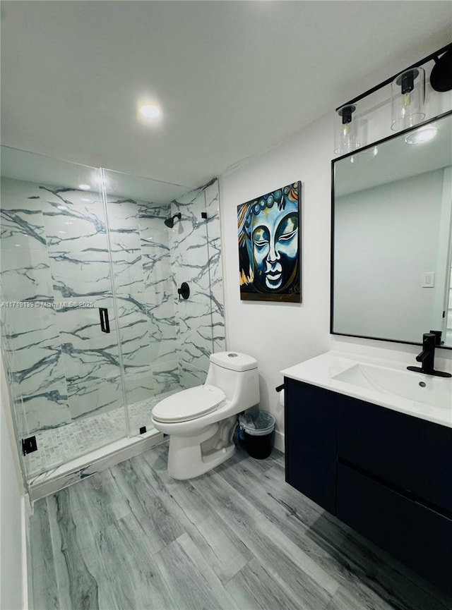 bathroom featuring hardwood / wood-style floors, vanity, a shower with door, and toilet