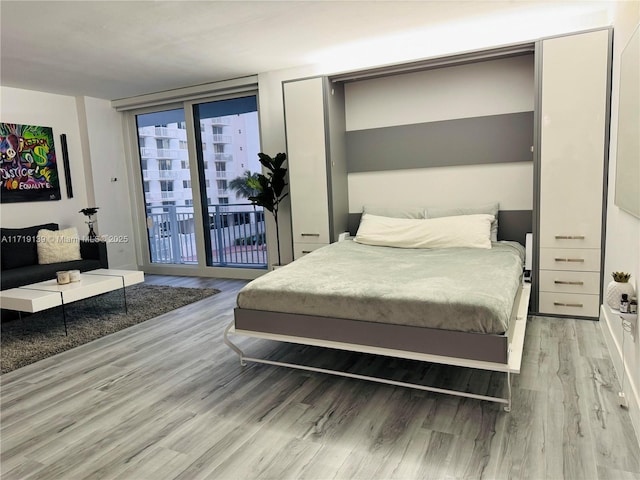 bedroom featuring access to outside, light hardwood / wood-style flooring, and a wall of windows